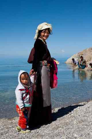 纳木错湖边散步的藏区妇女图片手机壁纸