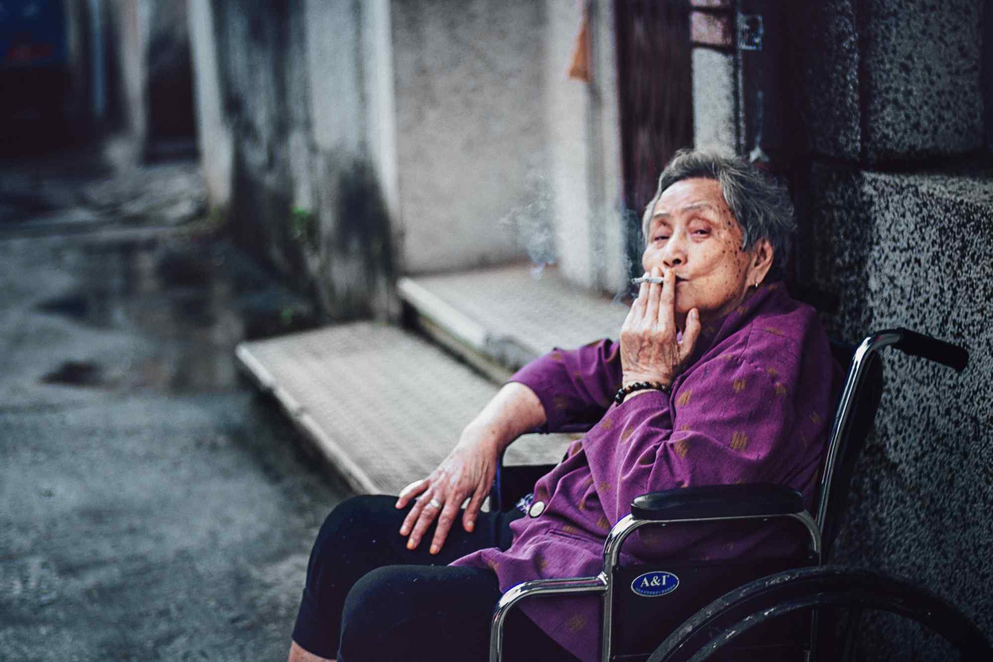 坐在轮椅上抽烟的老奶奶人物摄影图片
