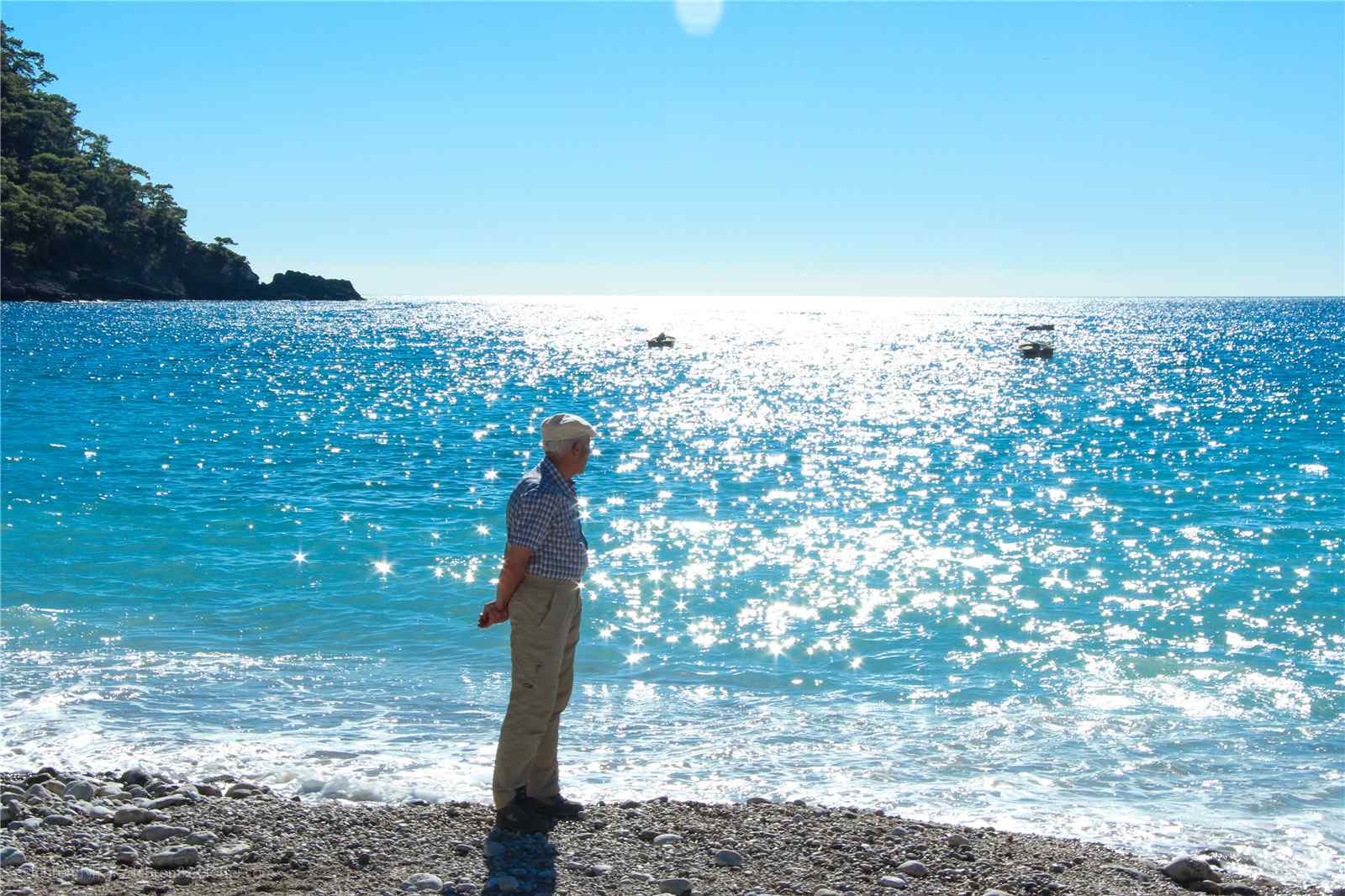 老人遥望波光粼粼的海边风景图片桌面壁纸